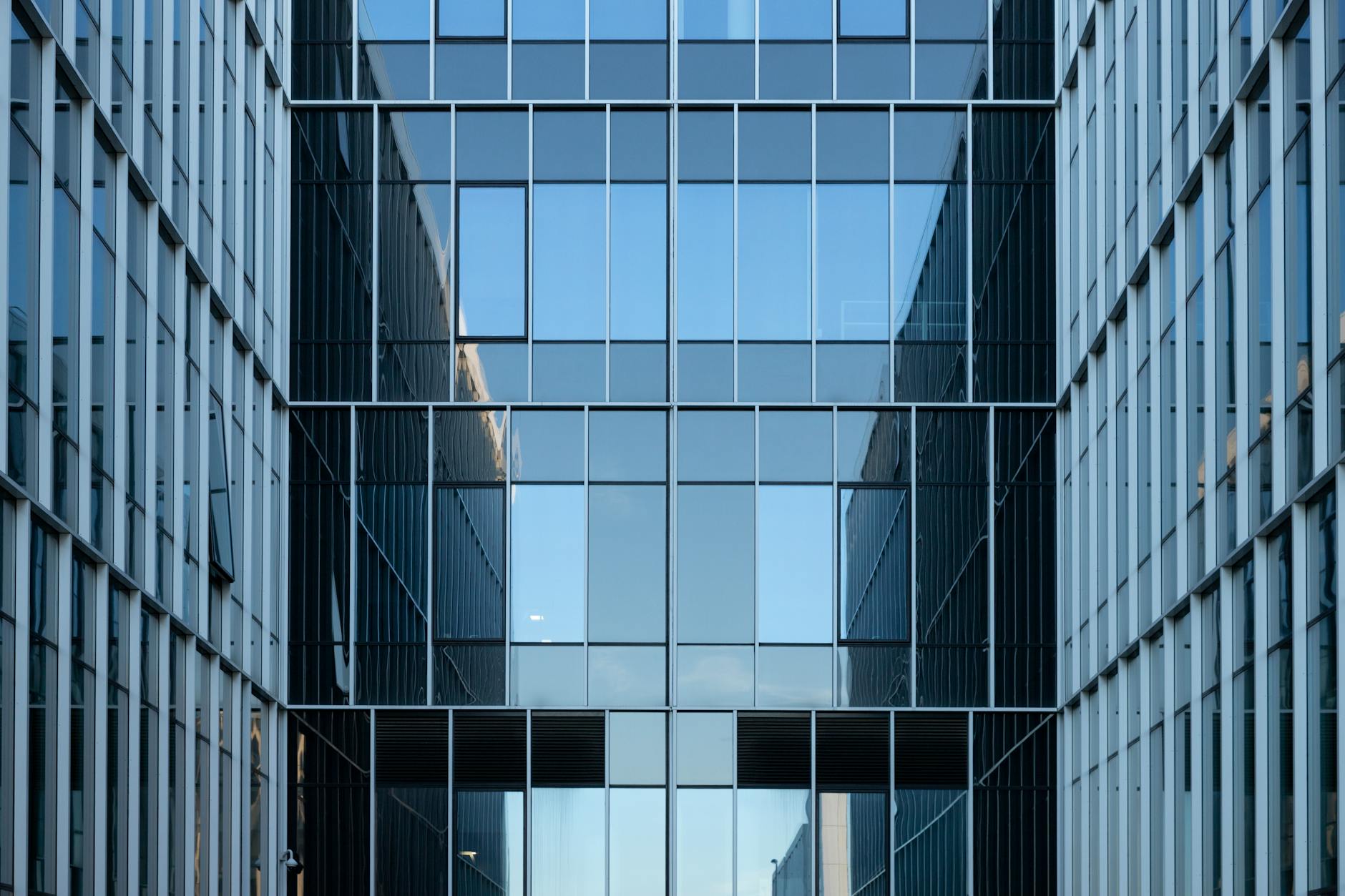 Contemporary building facade with reflective glass windows in an urban environment. (Photo by Mindaugas U on Pexels)