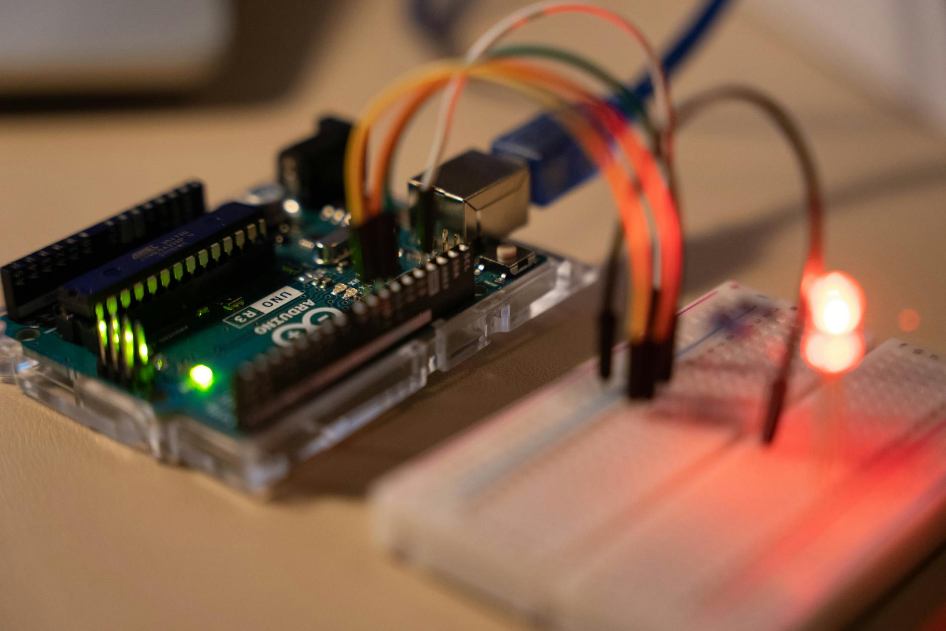Close-up of Arduino microcontroller connected to a breadboard with a glowing LED. (Photo by Chengxin Zhao on Pexels)