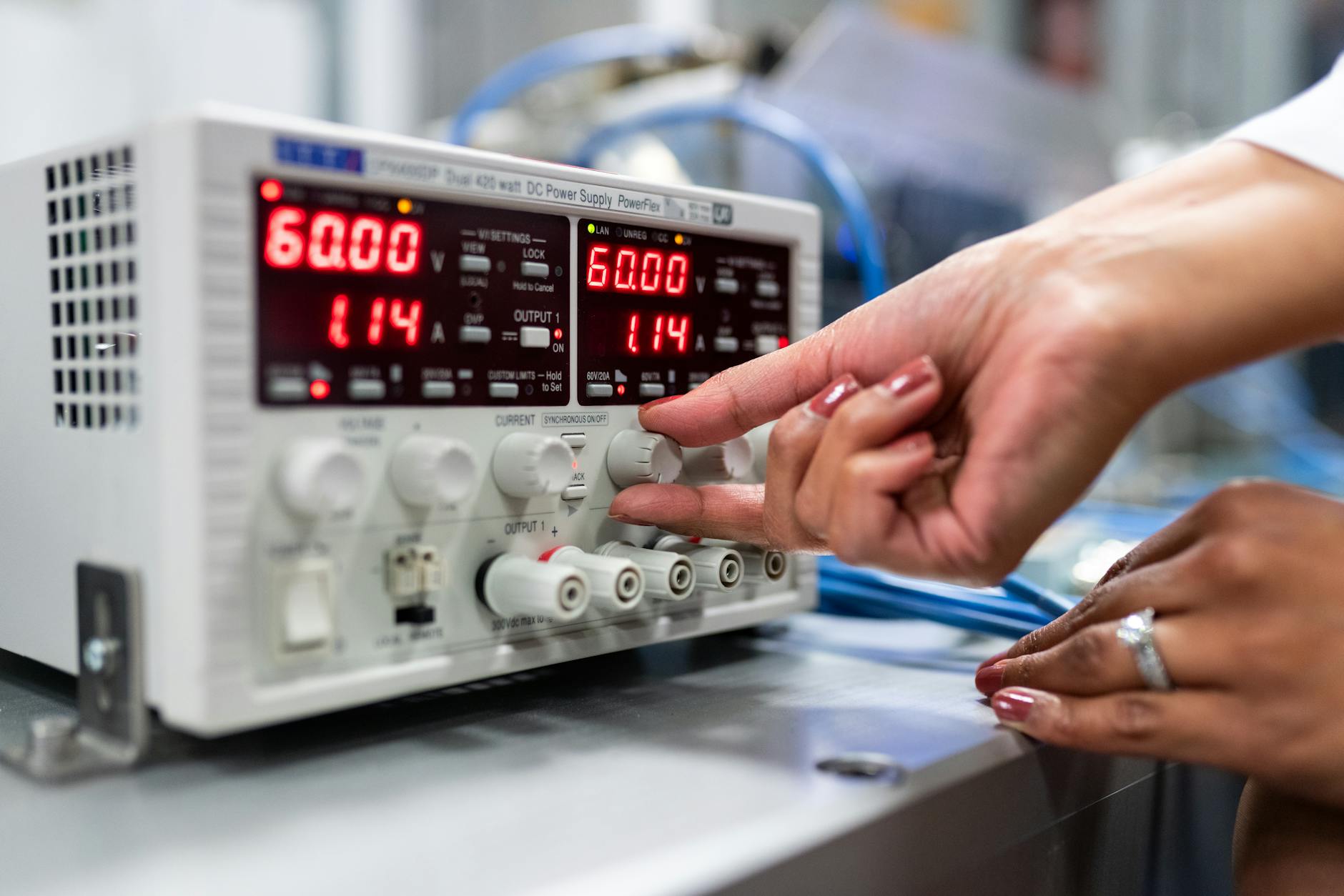 Close-up of a woman adjusting a DC power supply in a lab setting, indicating a hands-on approach ... (Photo by ThisIsEngineering on Pexels)