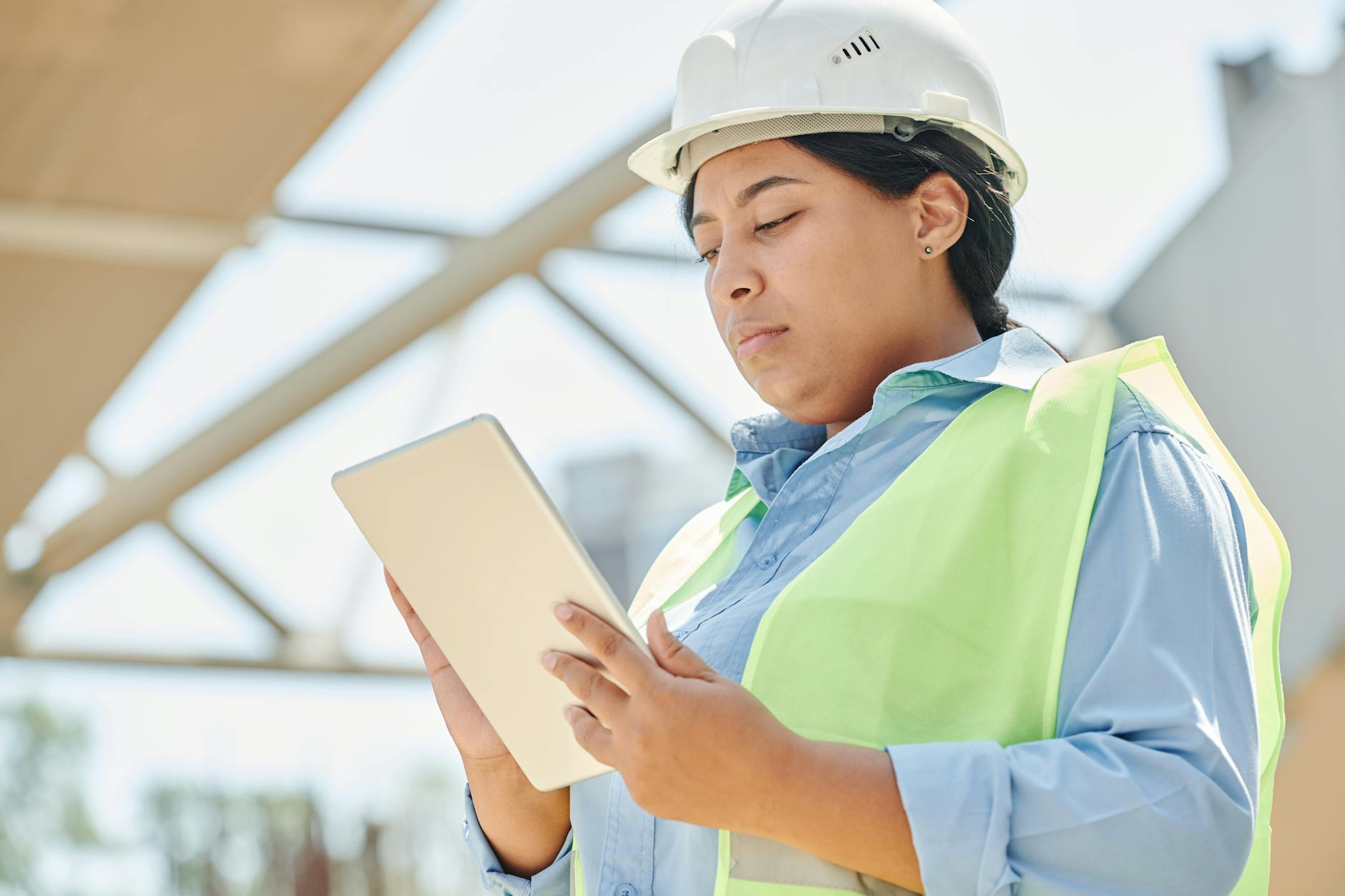 Confident female engineer in hard hat using a tablet computer at an outdoor construction site. (Photo by Mikael Blomkvist on Pexels)